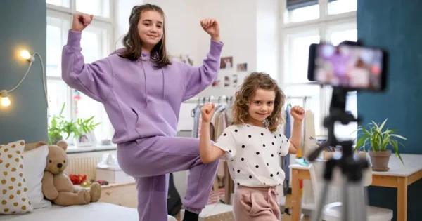 A teenager girl and a child filming themselves dancing on a smartphone